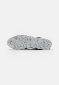 Suela de zapato en goma gris con un patrón texturizado, que presenta diseños de banda de rodadura distintos y un logo en el centro.
