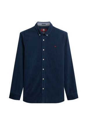 Chemise en velours côtelé bleu marine avec col boutonné, manches longues et un logo rouge sur la poitrine. Elle présente des boutons blancs et un tissu texturé.