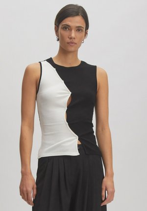 Sleeveless top with a black and white color block design. Features a ribbed texture and button accent along the side for closure.