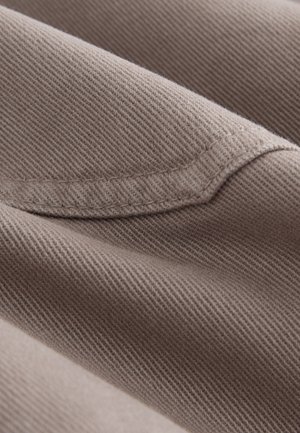 Tissu brun texturé avec une finition lisse, présentant des motifs de tissage diagonaux et un éclat subtil, mettant en valeur un design plié.