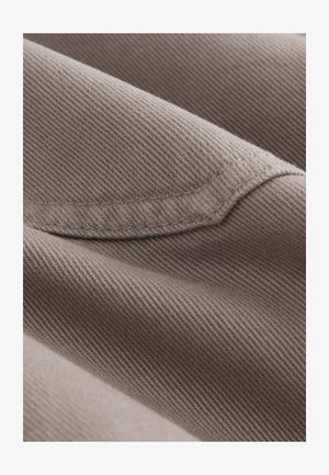 Tissu brun texturé avec une finition lisse, présentant des motifs de tissage diagonaux et un éclat subtil, mettant en valeur un design plié.