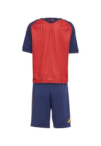 Červeno-tmavomodrý futbalový dres s krátkym rukávom so zvislými vzormi a žltými akcentmi, v kombinácii so zodpovedajúcimi šortkami.
