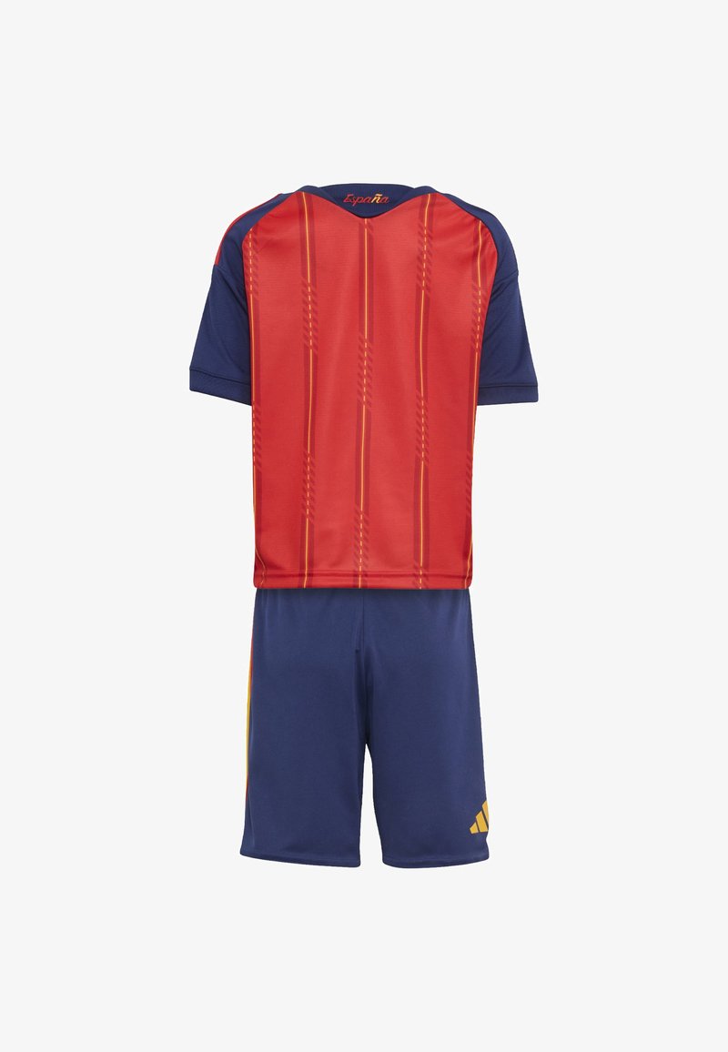 Conjunto de futebol vermelho e azul-marinho com camisa de manga curta com padrões verticais e detalhes em amarelo, combinado com calções a condizer.