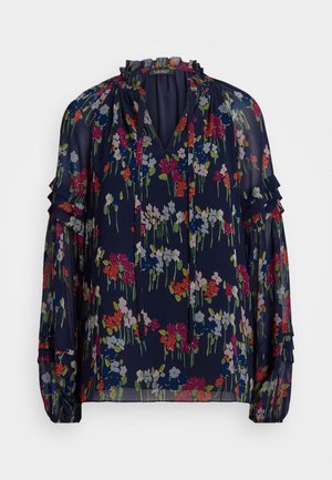 Laivastonsininen pusero, jossa on kukallinen kuosi, pitkät hihat, röyhelökoristeet ja V-kaula-aukko. Valmistettu kevyestä, läpikuultavasta kankaasta.