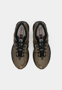 Brown mesh sneakers with black accents, featuring a textured surface, prominent lacing system, and a cushioned sole. Model 1906.