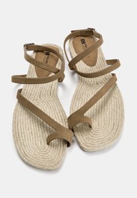 Tan sandalen met meerdere zachte banden en een gevlochten jute binnenzool. Voorzien van een platte zool en een verstelbare gesp voor de pasvorm.