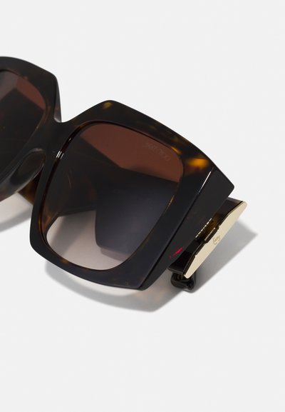 Oversized sunglasses with a tortoiseshell plastic frame, dark brown gradient lenses, and gold-tone hardware accent on the side.