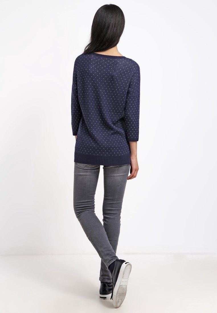 Mörkblå tröja med lös passform, ¾-långa ärmar och vita prickar. Matchad med grå skinny jeans och svarta sneakers.