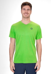 Camisa atlética verde de manga corta con escote en V y tejido texturizado; presenta un pequeño logo en azul marino en la parte superior izquierda del pecho.
