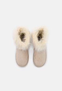 Beige Wildleder-Booties mit kremfarbiger Fellkante, runder Spitze und weicher Textur. Glatte Oberfläche mit gesteppten Kanten, entworfen für Wärme und Komfort.