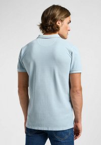 Ljusblå polo t-shirt i mjukt tyg, med klassisk krage och korta ärmar, med en slät textur och subtila sömdetaljer.