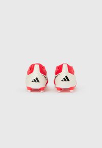 Ζευγάρι από κόκκινα και λευκά αθλητικά παπούτσια Adidas, φαίνονται από πίσω σε λευκό φόντο.