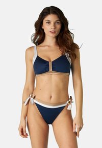 Bikini blu navy con un tessuto testurizzato. Il top presenta un design arricciato, accenti beige e lacci regolabili sui lati del bikini.