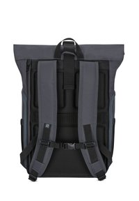 Gray roll-top backpack with padded mesh back panel, adjustable straps, and buckle closure. Features various textured materials and seams.