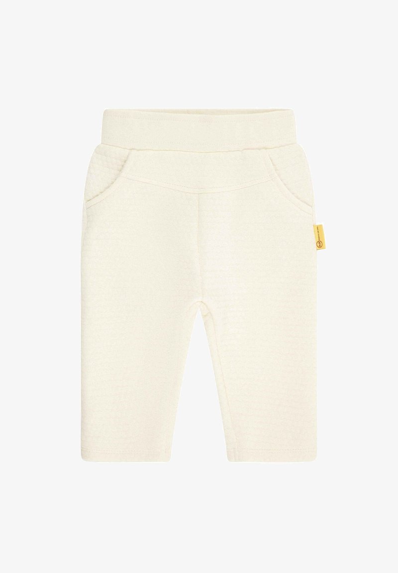 Pantalon pour bébé de couleur crème douce, avec taille élastique, poches avant et petite étiquette jaune sur la couture latérale.