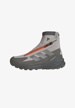 Gray waterproof mid-top hiking boots with an orange zip, textured sole, and three stripes design on the side. Features GORE-TEX material.