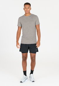 Ljusgrå kamouflage t-shirt med kort ärm i kombination med svarta shorts och grå sportskor. Enkel design med minimal detaljer.