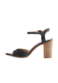 Sandal cu toc negru, cu vârful deschis, panou din piele texturată și curea ajustabilă la glezna, având un toc din lemn.