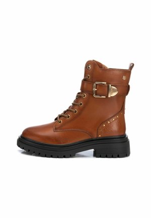 Botas ankle de cuero marrón con punta redondeada, cordones, detalle de hebilla dorada y acentos con tachuelas en el lateral. Suela de goma para mayor tracción.