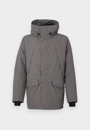 Harmaa eristysyksikkö, jossa on korkea kaulus, vetoketju ja kaksi etutaskua. Varustettu mustilla hihoilla ja huomaamattomilla ommelkoristeilla.