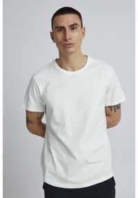 Bílý bavlněný tričko s kulatým výstřihem a krátkým rukávem, s hladkou strukturou a minimalistickým designem.