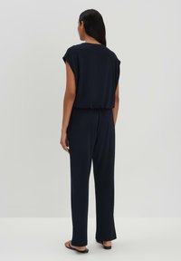 Marine jumpsuit met korte mouwen, ruime pasvorm en taps toelopende benen, met een subtiele geplooide tailleband voor een comfortabele silhouet.