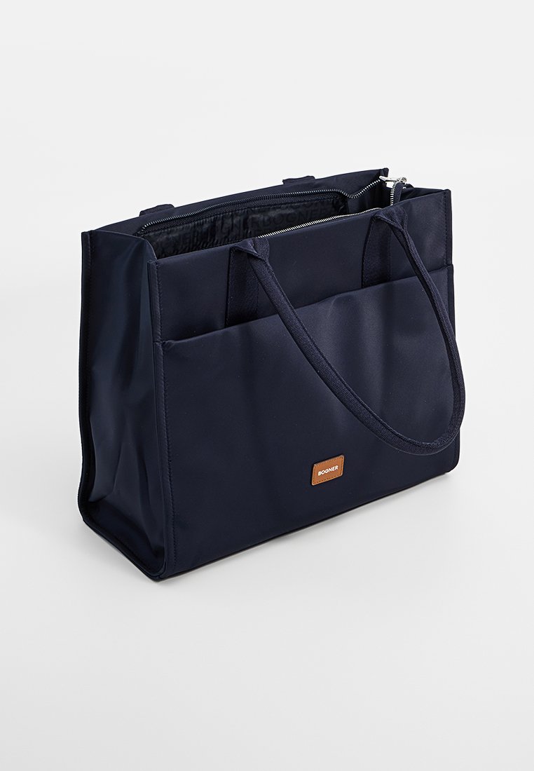 Navyblaue rechteckige Tragetasche mit doppelten Griffen, einer frontalen Einschubtasche und silbernem Reißverschluss, versehen mit einem kleinen braunen Etikett mit der Aufschrift "Boogner."