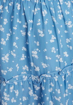 Svetlo modrá látka s malými bielymi kvetinovými vzormi, s volánovým švom a jemným, textúrovaným povrchom. Vhodné na neformálne nosenie.