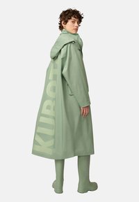 Mint green raincoat with a hood, featuring a large KUBOTA logo on the side. Matching knee-high boots complete the outfit.