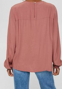 Langärmlige Bluse in staubrosa mit rundem Ausschnitt und Knopfverschluss auf der Rückseite. Weicher, fließender Stoff sorgt für eine entspannte Passform.