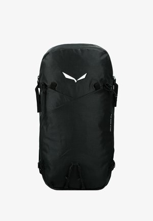 Mochila rectangular negra con correas frontales, logo blanco cerca de la parte superior y texto "Sella Tour 30 W" en el lateral sobre un fondo blanco.