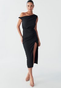 Schwarzes, schulterfreies Kleid mit gerafften Details, Seitenschlitz und tailliertem Schnitt. Hergestellt aus strukturiertem Stoff, knielang mit fließendem Fall.