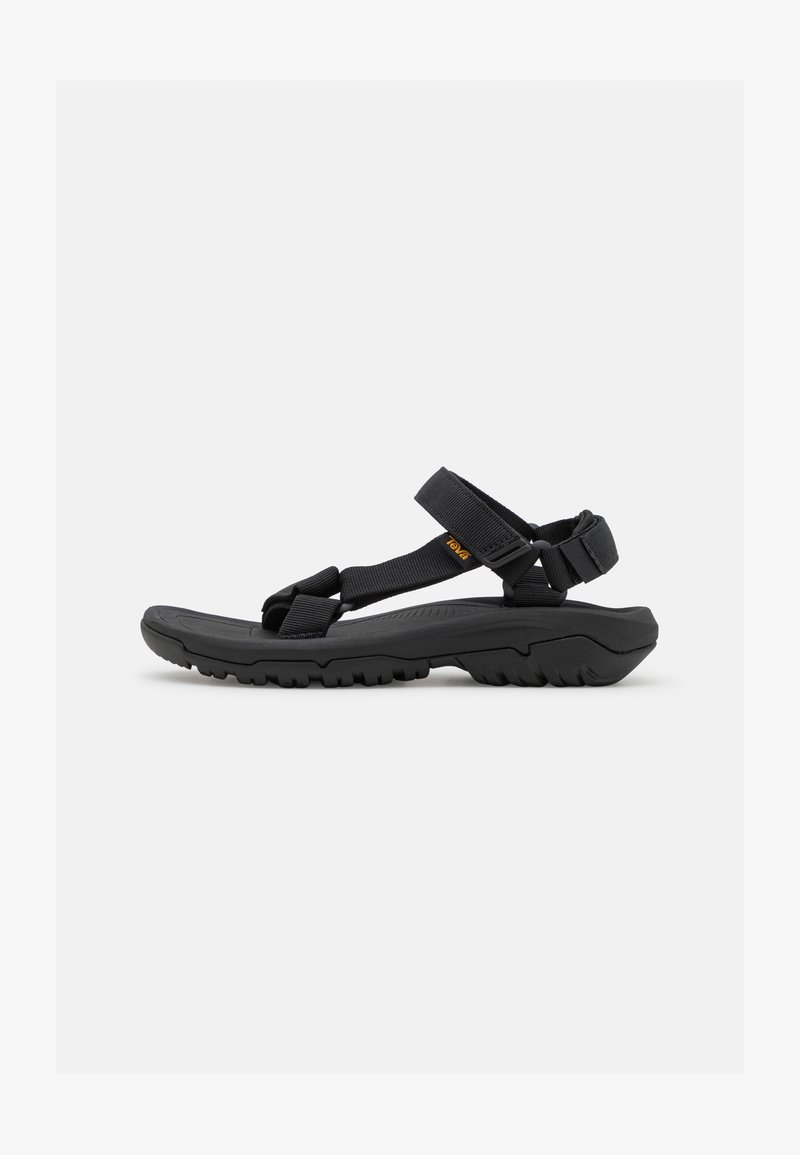 Black sandals with a textured rubber sole, adjustable fabric straps, and minimalist design features. Notable brand logo in orange.