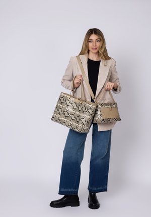 Due borsette in esposizione: una grande, beige, con motivo in pelle di serpente, e una più piccola, beige uniforme, entrambe con manici a spalla e decorazioni in metallo.