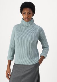 Light blue ribbed turtleneck sweater with three-quarter sleeves and rolled cuffs, made from soft knit fabric. Features a fitted silhouette.