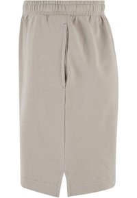 Jupe beige longueur genou avec taille élastique, fente avant à l'ourlet, et poches latérales verticales sur fond uni.