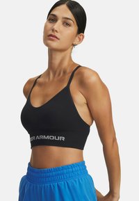 Zwarte sportbeha met een brede onderband waarop het "Under Armour"-logo in lichtgrijs is afgebeeld. Dunne bandjes en een naadloos ontwerp met een gladde textuur.