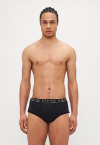 Schwarze Baumwollslips mit einem elastischen Bund in Markenqualität, die eine glatte Textur und eine enge Passform bieten. Minimalistisches Design, ohne sichtbare Muster.