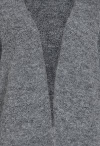 Gr�å stickad cardigan med V-ringad design, som har ett mjukt, texturerat tyg och en öppen front utan knappar eller stängningar.
