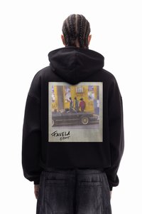 Schwarzer Hoodie mit einem großen rechteckigen Grafikdruck auf dem Rücken, der eine Straßenszene in gedämpften Farben zeigt, darunter eine Unterschrift.