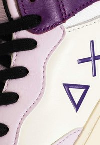 Sneaker bianco e lavanda con lacci neri, dotata di un accento viola e modelli geometrici. Materiali in pelle liscia e tessuto.