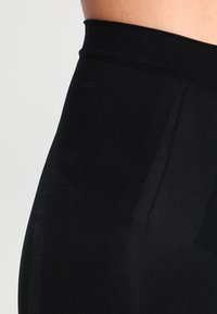 Czarne legginsy z wysokim stanem wykonane z teksturowanego materiału, z gładkim pasem w talii i bezszwowym krojem, z dyskretnymi detalami w postaci bocznych szwów.