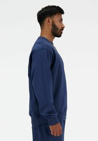 Sudadera de color azul marino hecha de suave algodón, con cuello de barco, puños acanalados y un corte relajado. Textura suave sin patrones visibles.