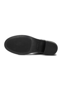 Suela de zapato negra con superficie de goma texturizada, surcos circulares y horizontales, que presenta un número de talla y el logotipo de la marca en relieve.