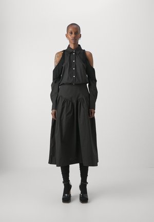 Completo di abbigliamento nero con una maglietta off-shoulder con dettagli di frange e una gonna fluida e arricciata. Tessuto liscio e solido con una vestibilità comoda.