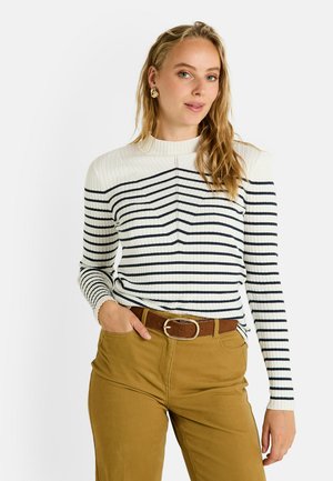 Pull côtelé à manches longues crème avec rayures horizontales bleu marine, doté d'un col montant et de détails texturés, associé à un pantalon marron ceinturé.