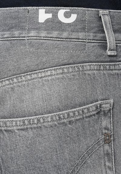 Γκρίζα τζιν παντελόνια με πίσω τσέπη, ορατές ραφές και ετικέτα με λευκό κείμενο. Το ύφασμα έχει λεία υφή και ξεθωριασμένο σχέδιο.