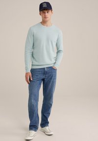 Svijetloplava pulover s rebrastim manžetama i rubom, nosi se s plavim trapericama i bijelim tenisicama. Crna kapa s bijelim naglaskom slova.