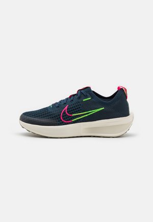 Nike sneakers med et navy mesh-overdel, lyserøde og grønne accenter, polstret krage, og en kraftig hvid mellemsål.