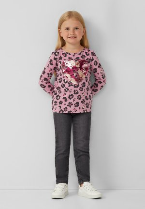 Rosa langärmliges Oberteil mit schwarzem Leopardenmuster und einem Pailletten-Herzdesign. Kombiniert mit dunklen Jeans und weißen Sneakers. Glatte Textur.